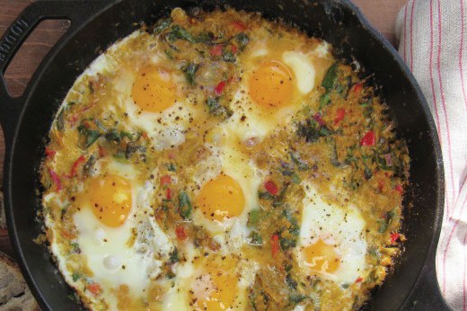 A cast iron pan full of green tomato shakshuka, which features tomatoes and eggs.